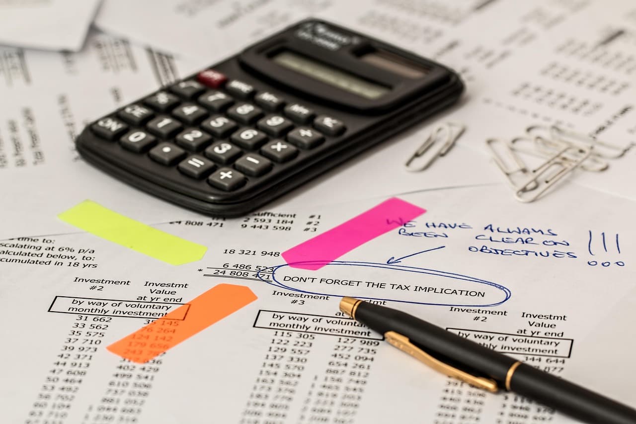 Calculatrice et stylo sur des documents financiers annotés